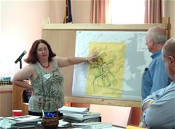 A woman talking while pointing at a map